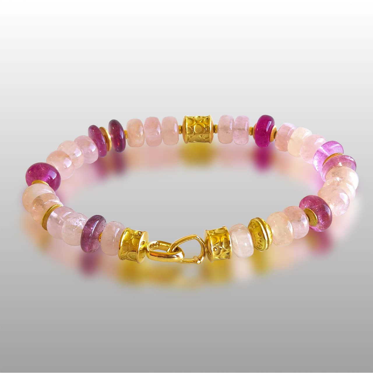 Bracelet made of various shades of pink stones and gold beads and clasp