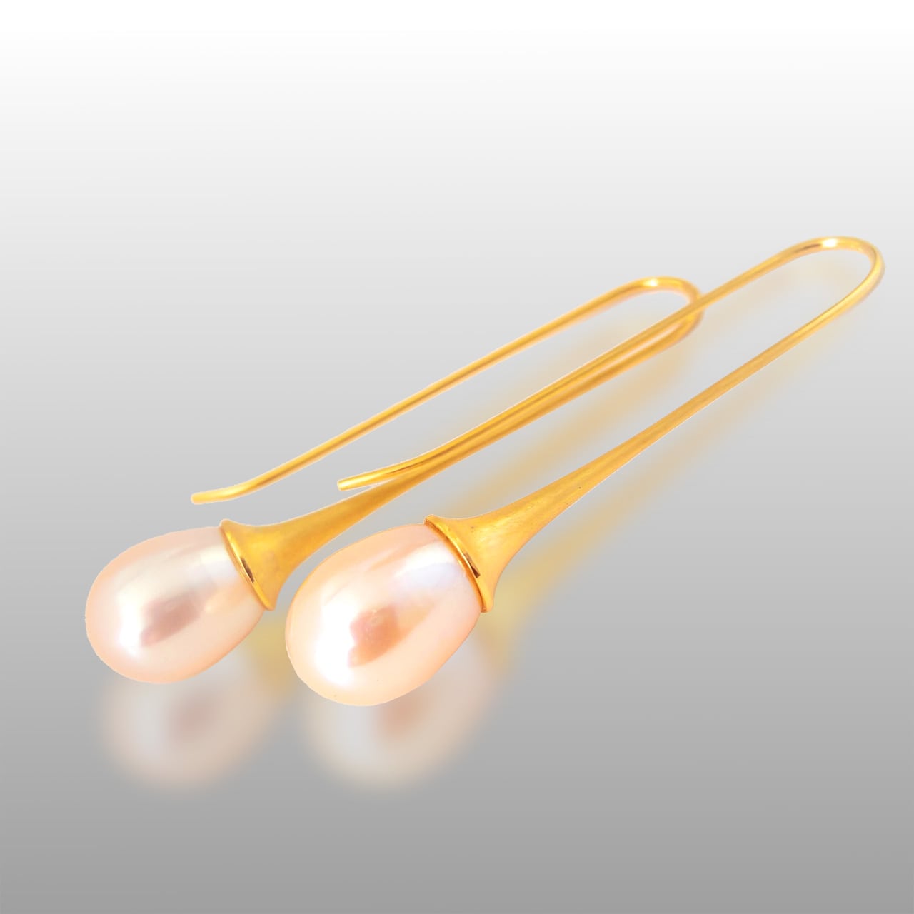 Long dangle 18k gold earrings with an oval shaped pink pearl at each end