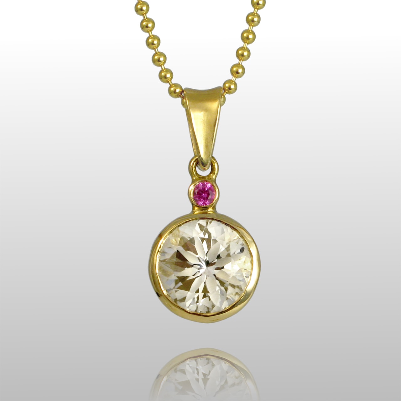 18k yellow gold pendant and a diamond and a small single pink gemstone above