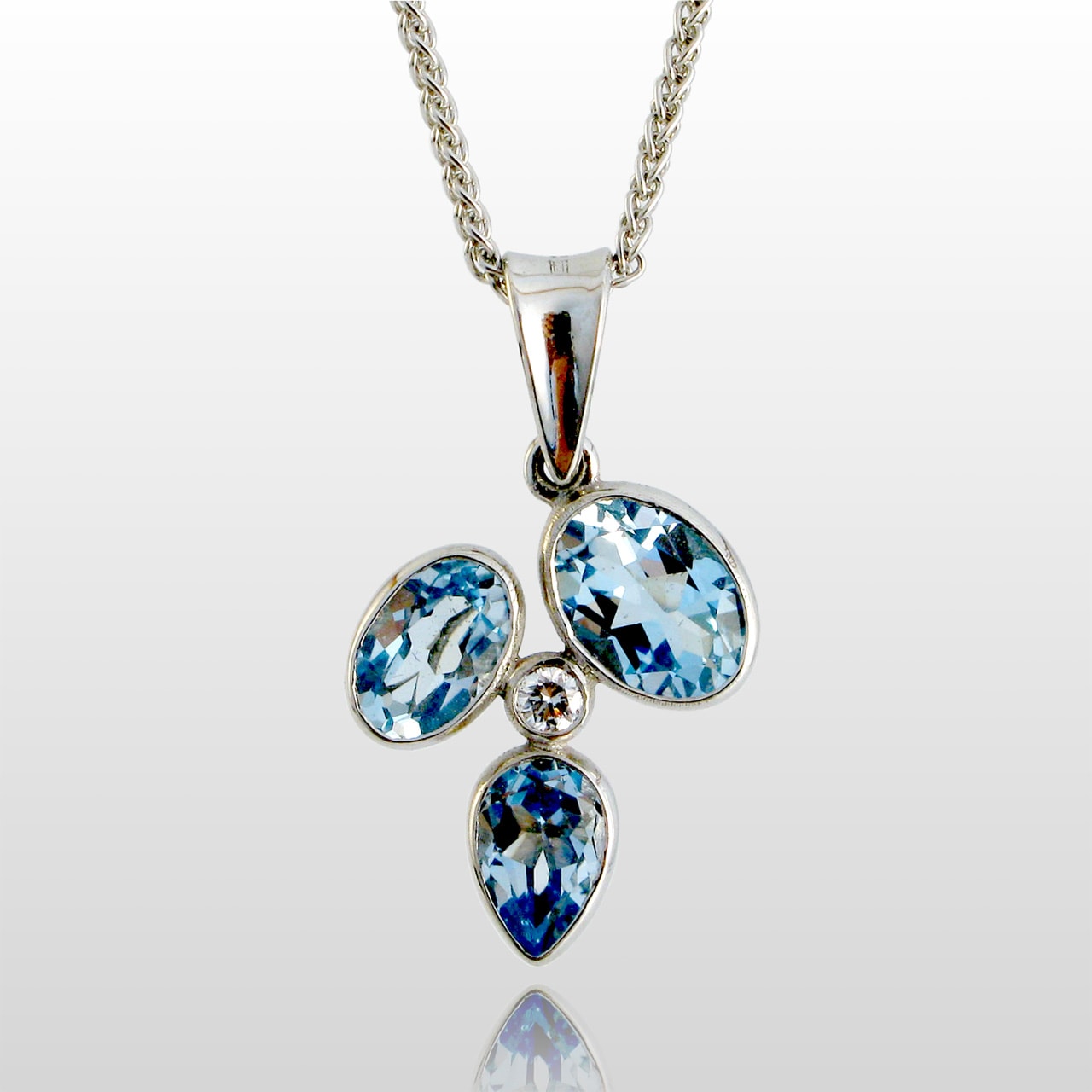 White gold pendant with 3 blue stones and a single diamond in the center