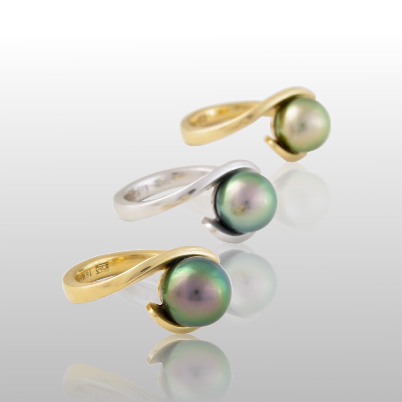 Three Tahitian pearl rings. Thin gold bands which wrap around the pearl