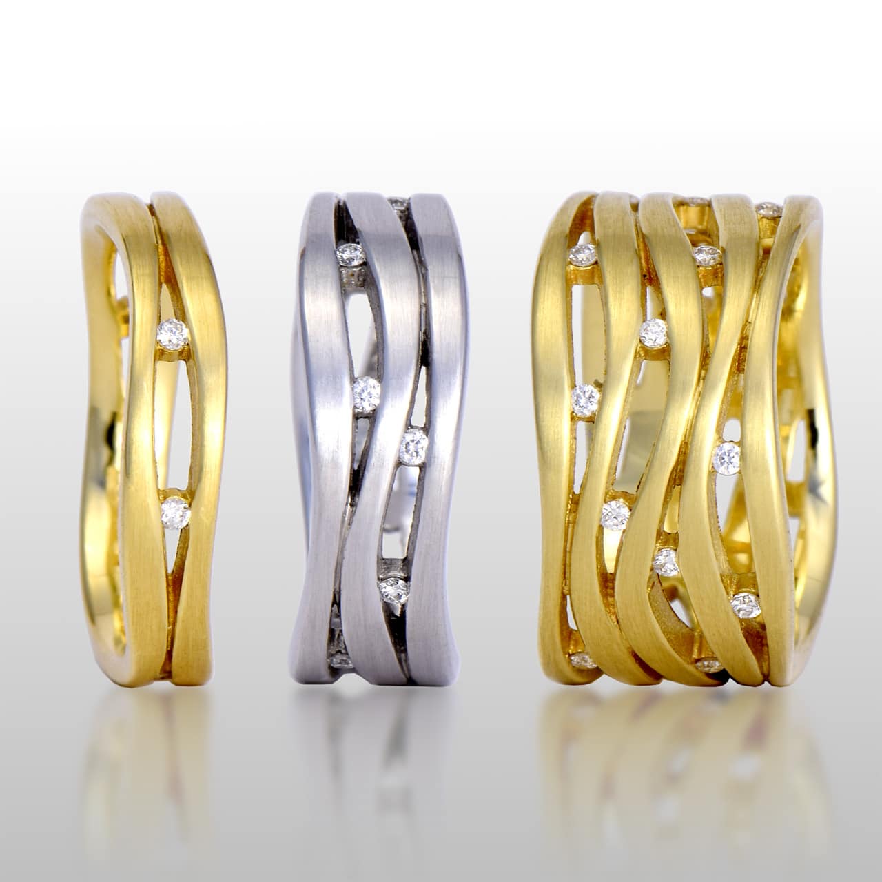 Three rings, two are yellow gold and one is white gold. All various widths and diamonds