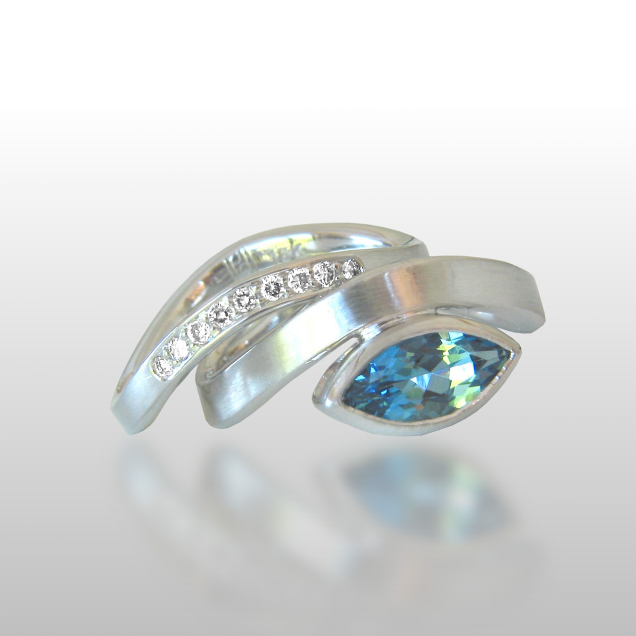 White gold ring set with a set of small diamonds and one large aquamarine stone cut into a unique shape