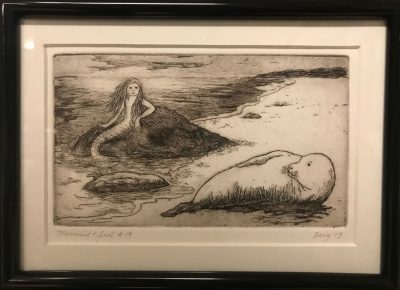 an original print of a mermaid and seal lying on the shore of a beach