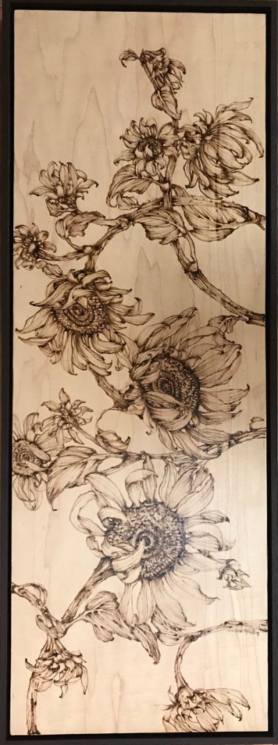 an original wood burned wall hanging of many sunflower plants. hung vertically