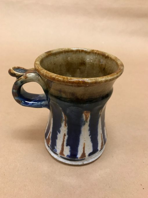 large ceramic mug with a thumb rest. Top is brown, neutral color. And the bottom two-thirds is navy blue and white colored