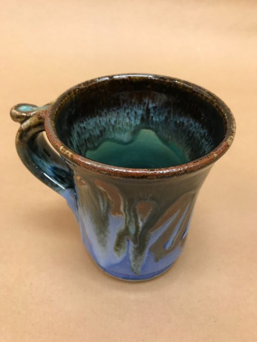 large ceramic mug with a wide rim and thumb rest. Brown, light and dark blue colors. Green, aqua colored inside