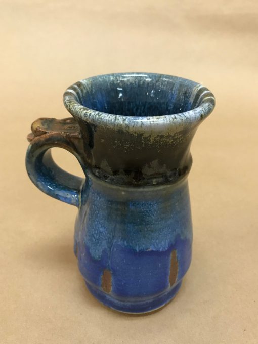 a ceramic mug that is royal blue and brown. With a thumb rest on the top of the handle