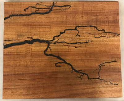 a original wall hanging made of Hawaiian Koa wood. Socked with electricity to form an organic design. Outline of electrical waves is black, against the wood grains.