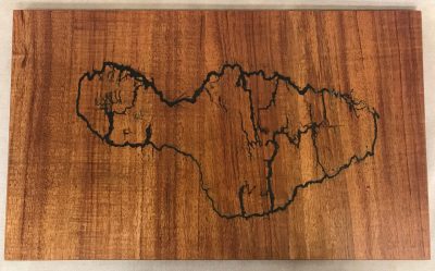 a original wall hanging made of Hawaiian Koa wood. Socked with electricity to form the shape of the island of Maui. Outline of electrical waves is black, against the wood grains.