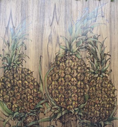 three pineapples woodburned and oil painted onto a teak wood panel.