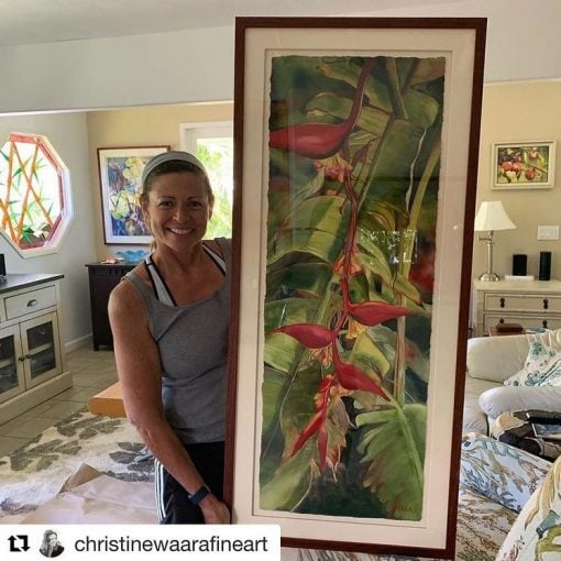 Christine Waara holding "Hanging Firelight Heliconia" framed watercolor painting